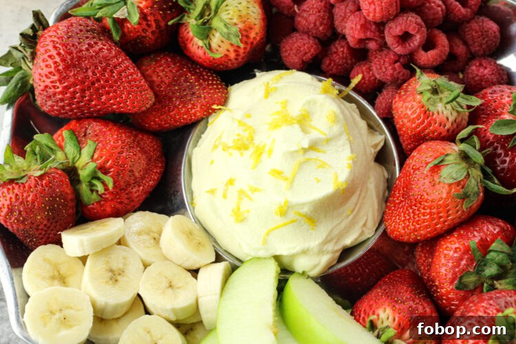 bananas, strawberries, raspberries and green apples surrounding yellow lemon fruit dip in the center