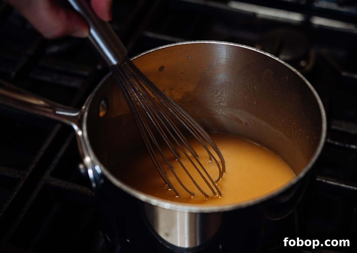 whisking toasted flour and brown butter mixture into simmering chicken broth.