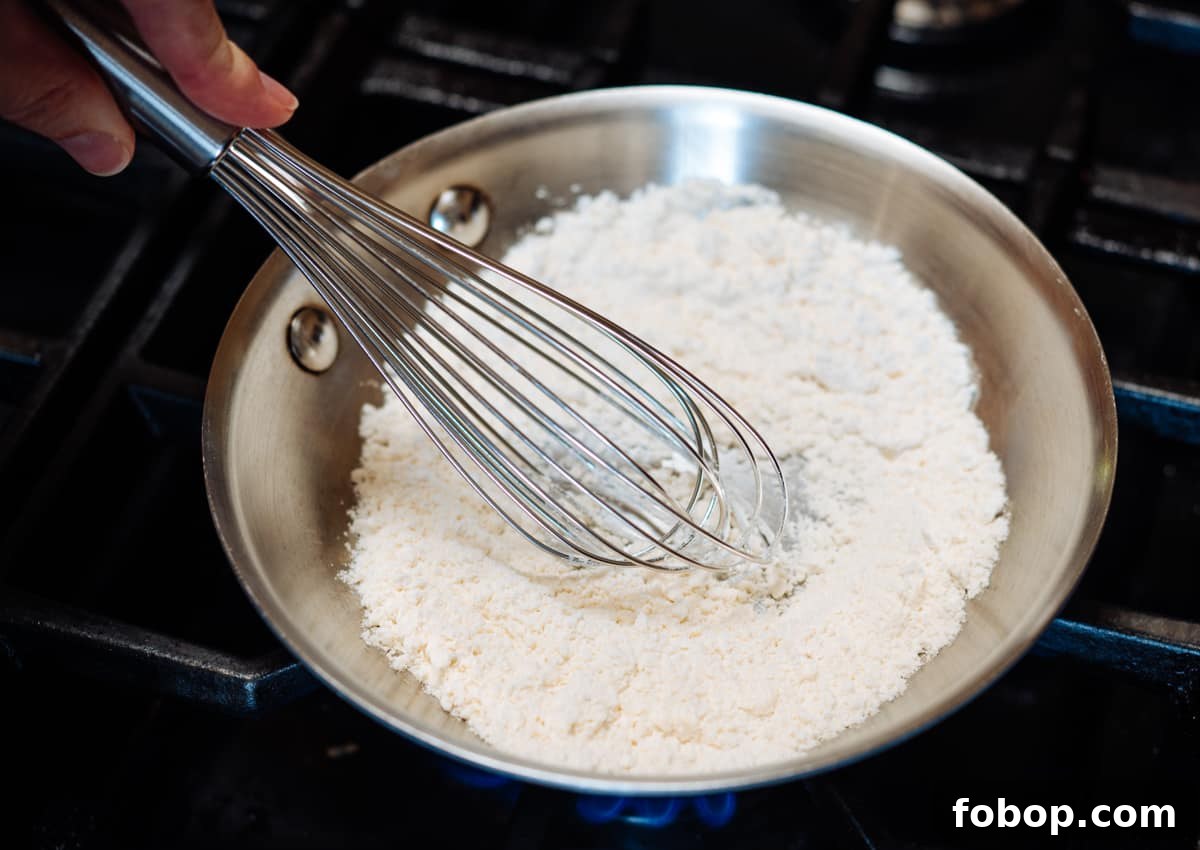 whisking white flour in a skillet.