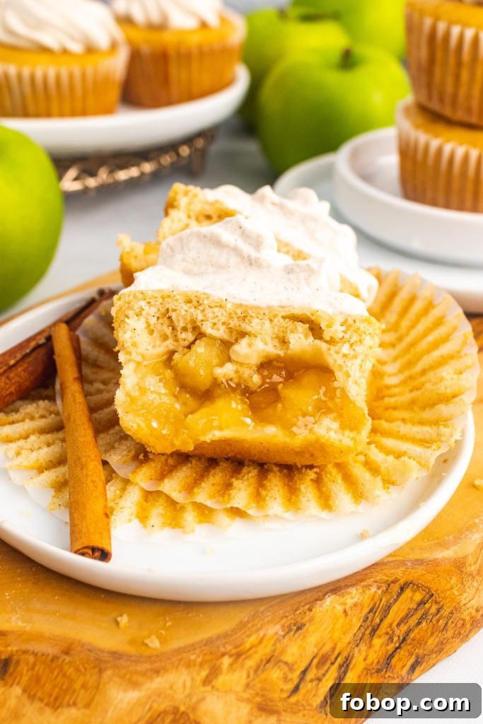 a frosted apple pie cupcake unwrapped and cut in half to reveal the pie filling hidden in the center