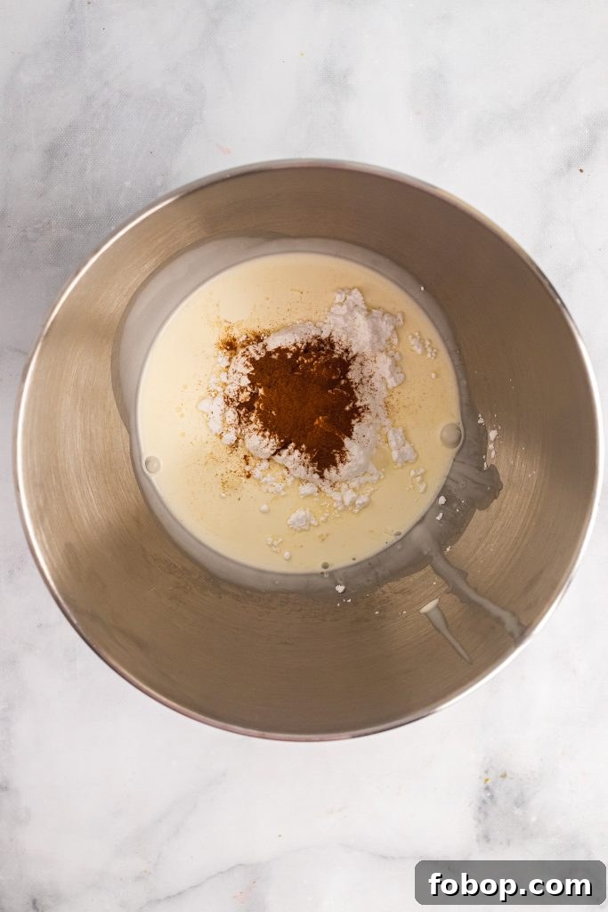 ingredients for cinnamon whipped cream shown in a stainless steel mixing bowl