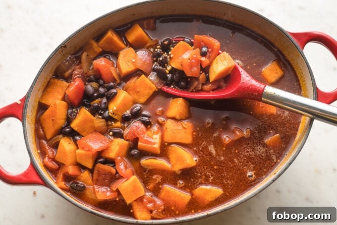 Sweet Potato and Black Bean Chili Recipe for Cozy Weeknights 6 Broth, tomatoes, and black beans added to pot.