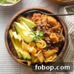 Sweet Potato and Black Bean Chili Recipe for Cozy Weeknights 10 Bowl of sweet potato black bean chili served with avocado, cilantro, and corn chips.
