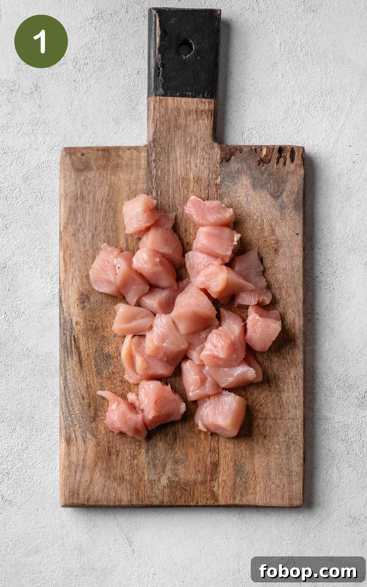 chicken cut into cubes on a cutting board.