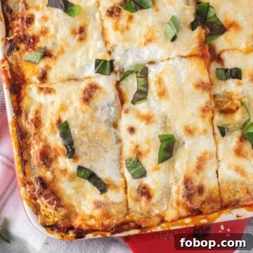 Ground meat lasagna in red baking dish on dish towel.
