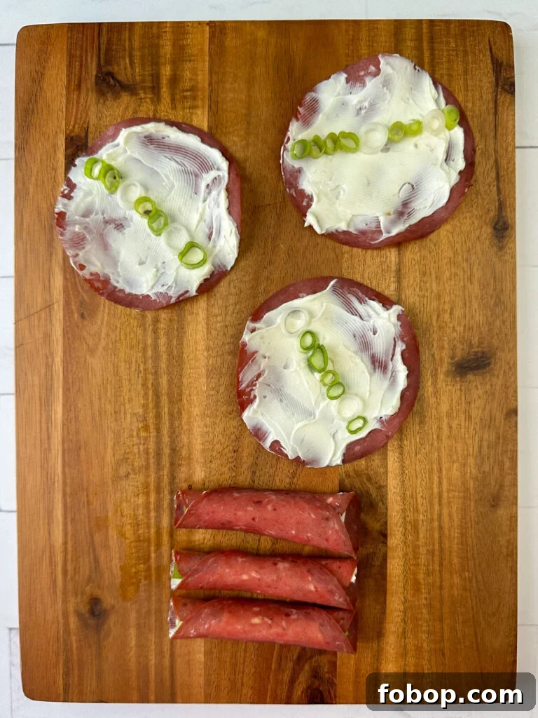 Savory Dried Beef Roll-Ups Recipe for Appetizers and Snacks 11 Three slices of dried beef with a row of sliced green onion in the center and three more roll-ups below on a wooden board.