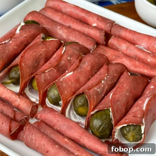 Savory Dried Beef Roll-Ups Recipe for Appetizers and Snacks 13 Close up of a variety of creamy dried beef and pickle roll-ups on a white plate.