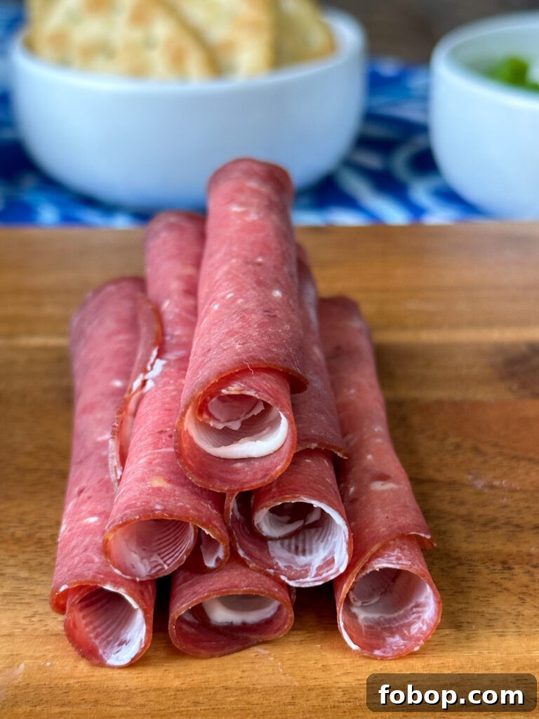 Savory Dried Beef Roll-Ups Recipe for Appetizers and Snacks 7 Close up of beef with a thin layer of rich cream cheese stacked on a brown board.
