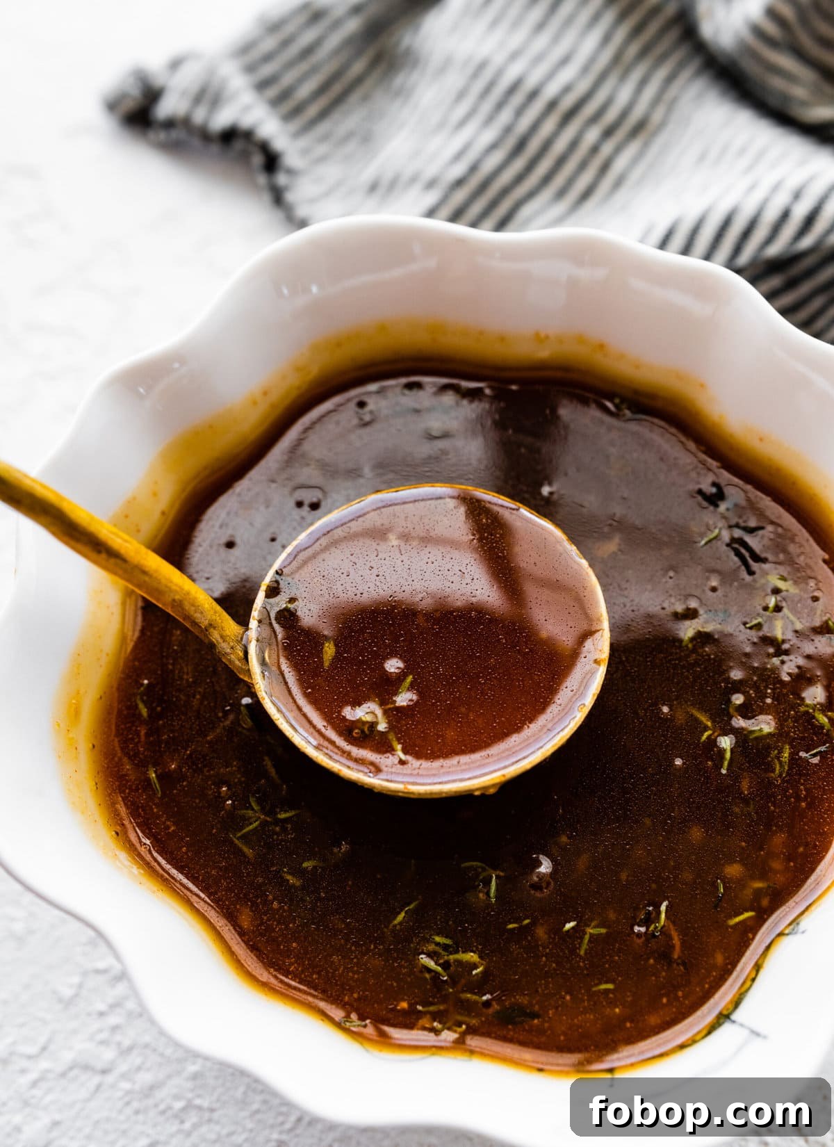 Thickened brown sugar glaze lifting up in a ladle from a bowl of more.