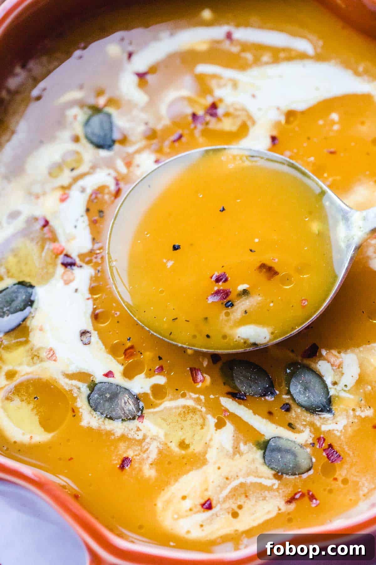 Vegan Pumpkin Soup garnished with fresh thyme, child flakes and pumpkin seeds