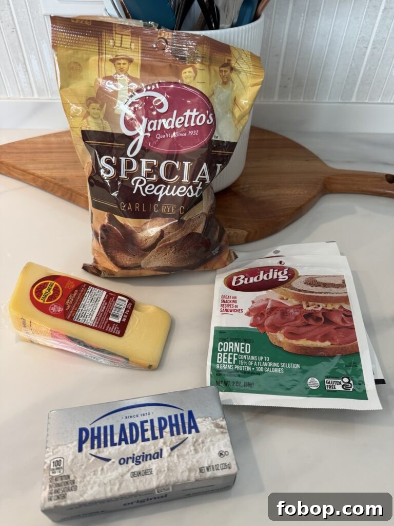 A bag of Gardetto rye chips, a wedge of Jarlsberg cheese, and a package of Buddig corned beef