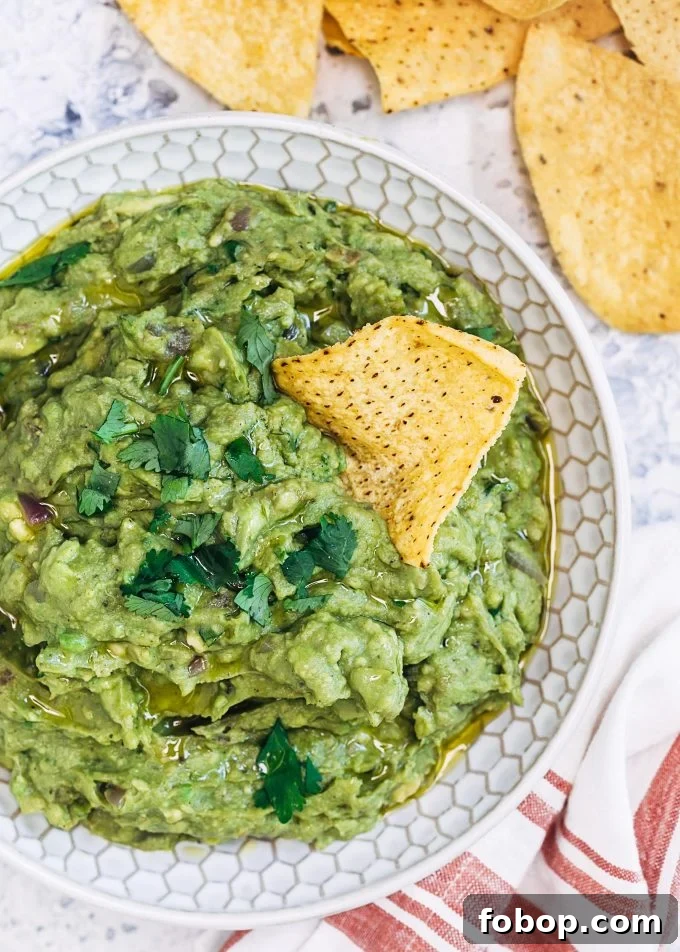 Smoky Grilled Avocado Guacamole Recipe for Backyard BBQs 5 grilled avocado guacamole in a bowl with a tortilla chip