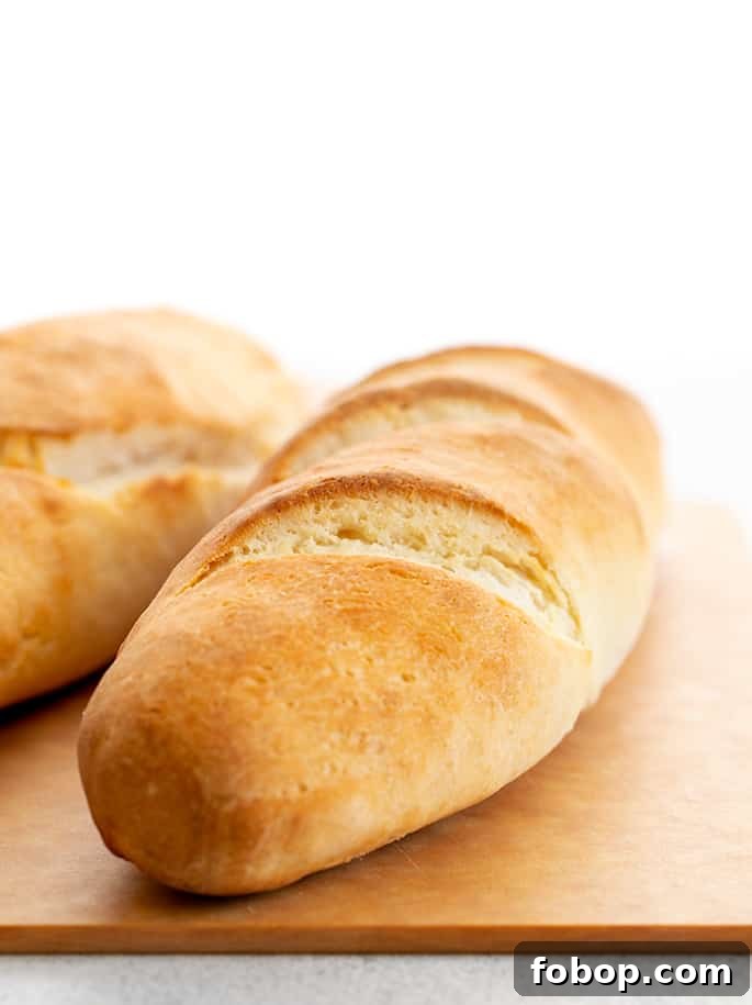 Crispy Gluten-Free French Baguettes: Artisan-Style Recipe 3 Two loaves of gluten free French bread baguettes on a light brown cutting board