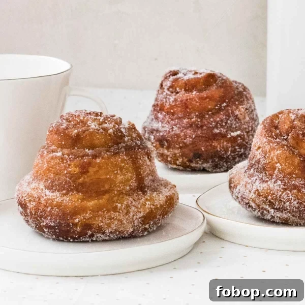 Perfectly Flaky Morning Buns: Cinnamon Sugar Pastry Recipe 9 A square image of three fresh morning buns on individual plates, covered in sugar.