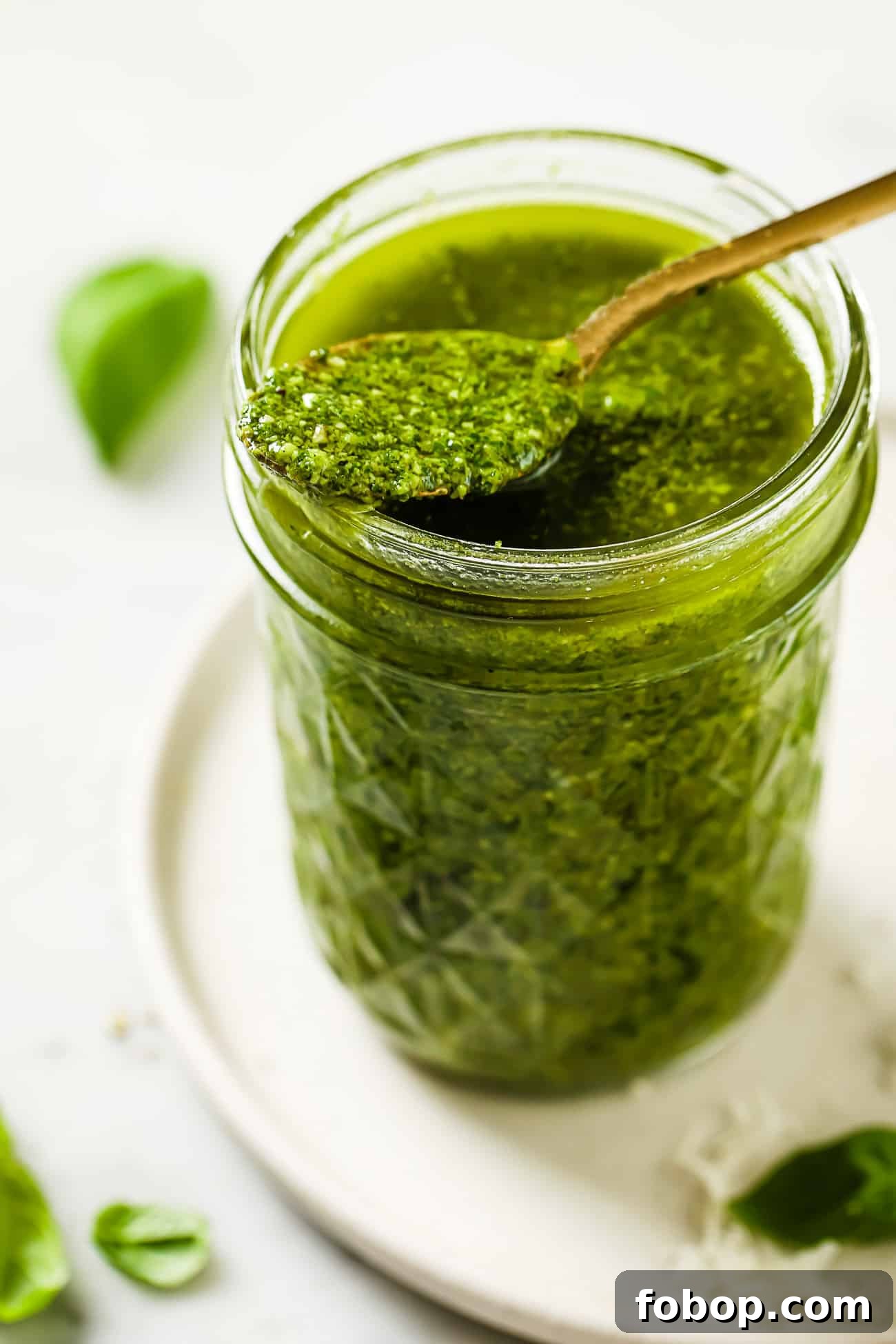 A spoonful of homemade basil pesto resting on top of a jar.