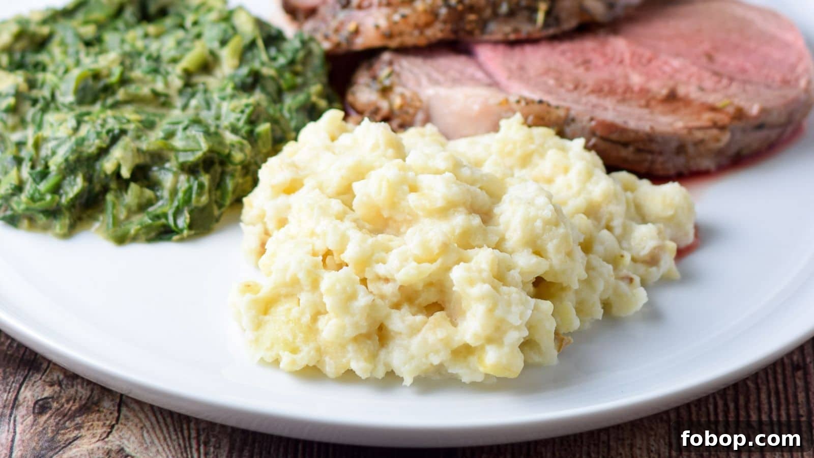 17 Flavor-Packed Side Dishes to Elevate Any Meal 13 A white plate with mashed celery root, spinach, and lamb