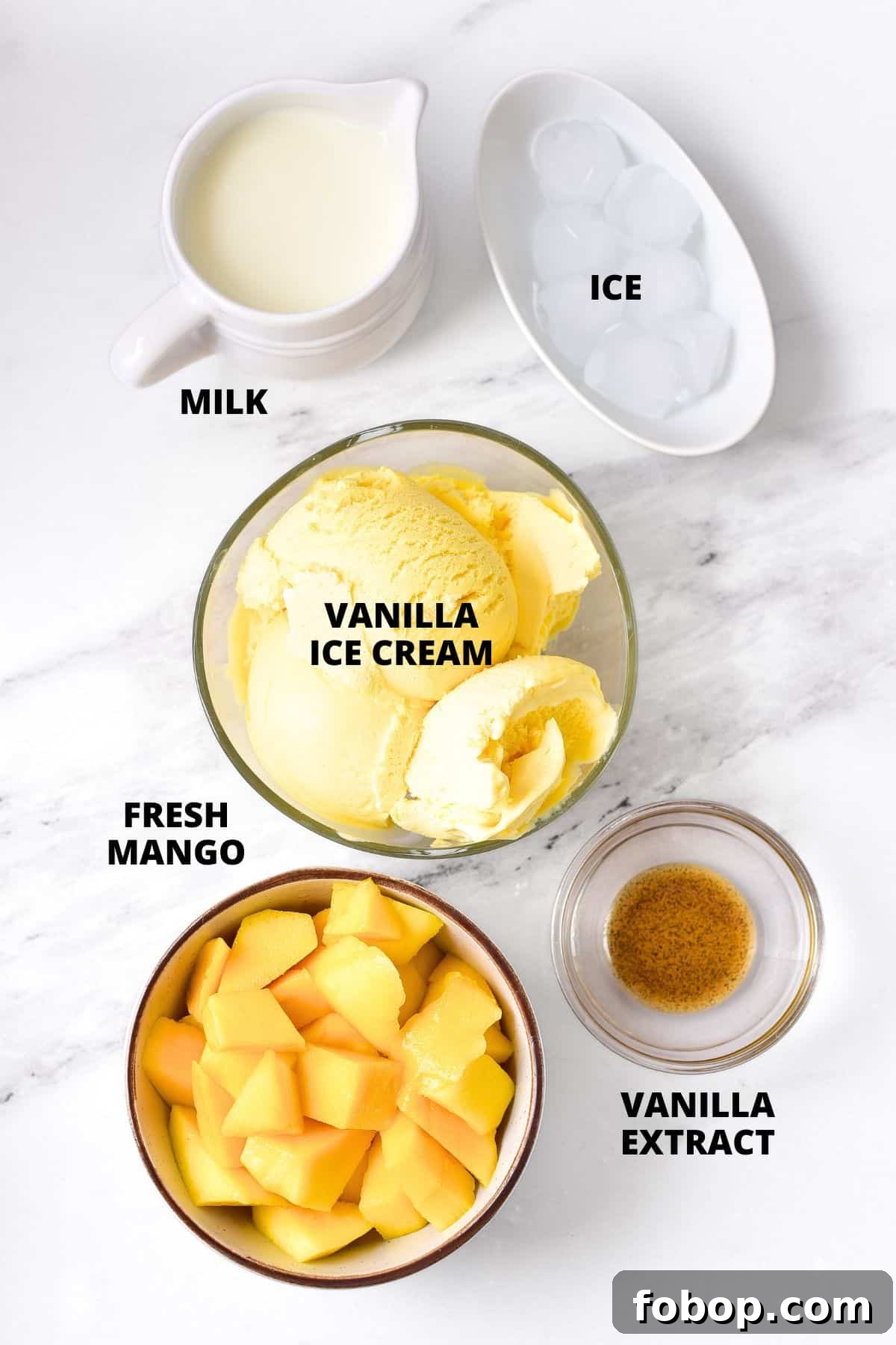 Ingredients for creamy mango milkshake recipe laid out on marble board.