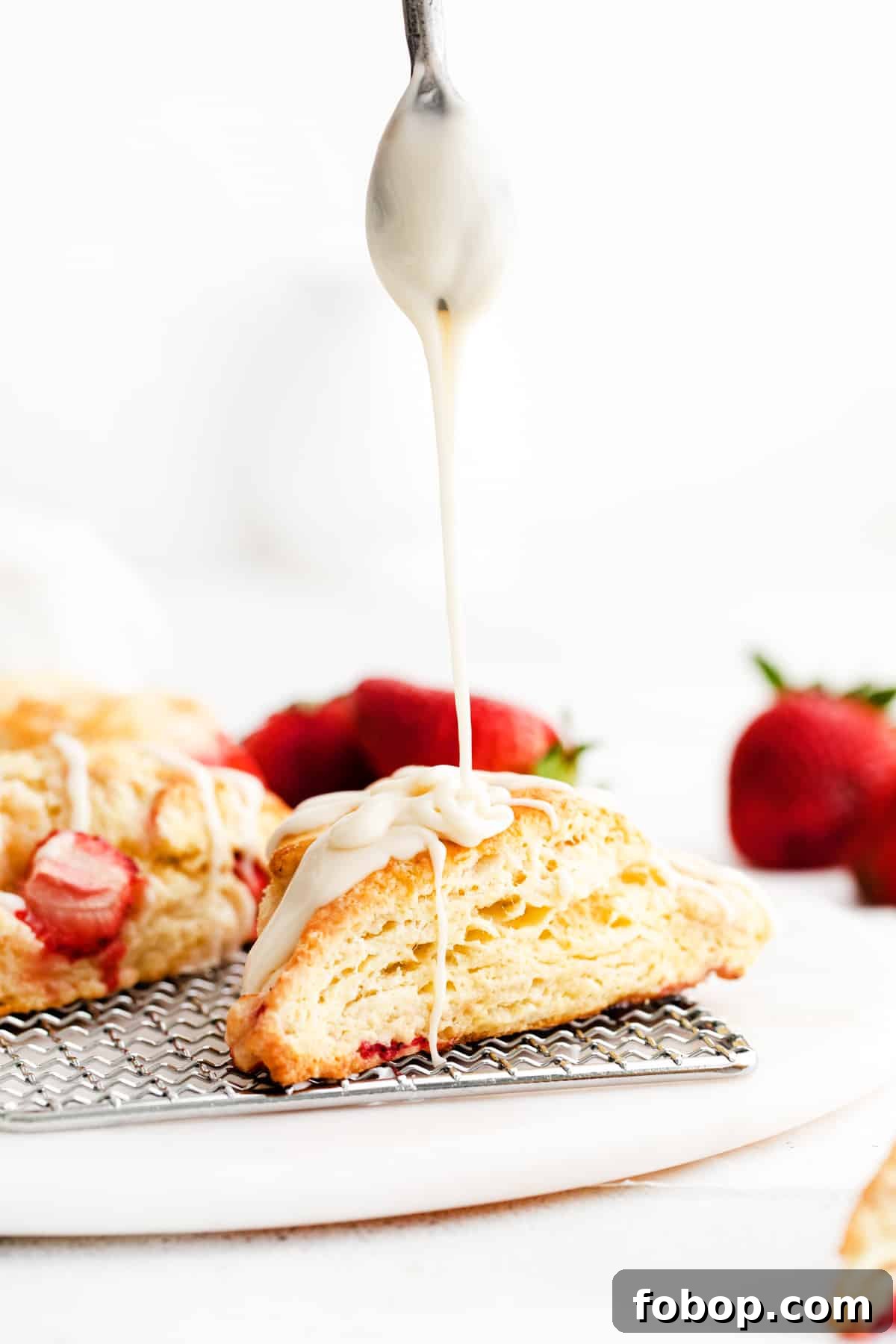 Spoon drizzling glaze on top of scone