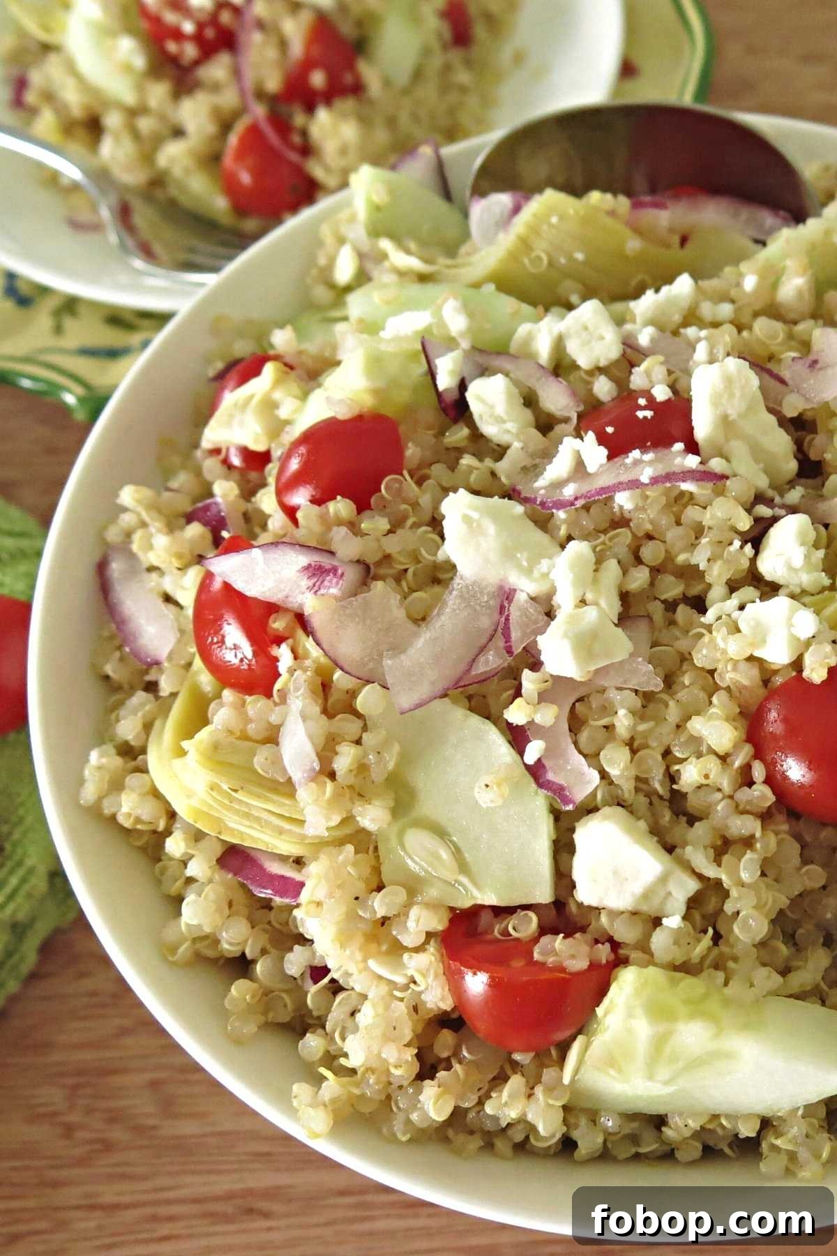 Greek Quinoa Salad with Red Wine Vinaigrette Recipe 3 Greek quinoa salad with artichokes, cucumbers, grape tomatoes, and onions in a large serving bowl.
