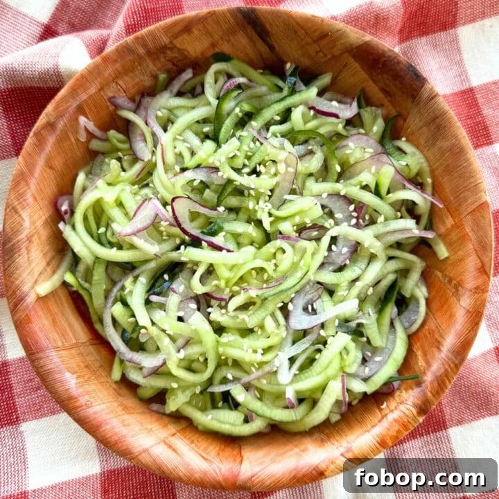 Easy cucumber salad with rice vinegar, red onion and sesame seeds in a brown bowl.