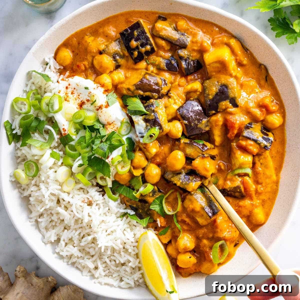 30 Delicious Eggplant Recipes for Every Meal 17 Eggplant curry with basmati rice, yogurt, and a spoon.