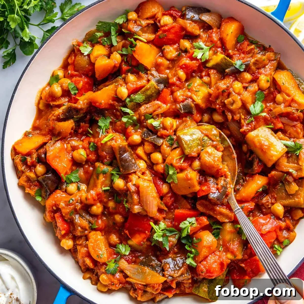 30 Delicious Eggplant Recipes for Every Meal 19 Tagine in a blue skillet with a silver spoon.