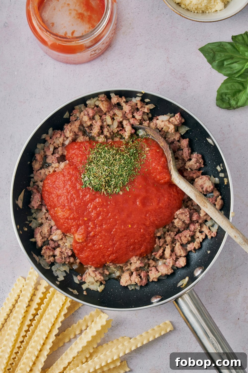 A skillet with ground beef, red sauce, and seasonings.