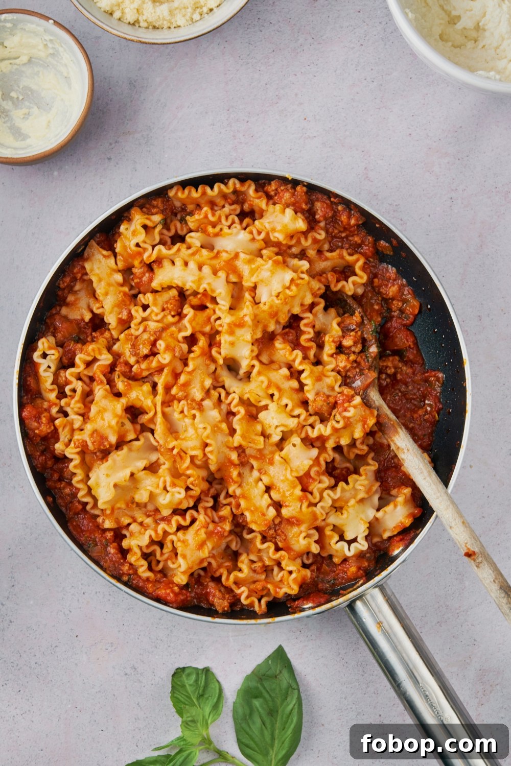 A skillet with pasta mixed with red sauce.