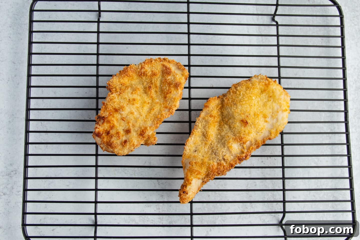 This is a picture of a chicken cutlets resting on a metal rack.