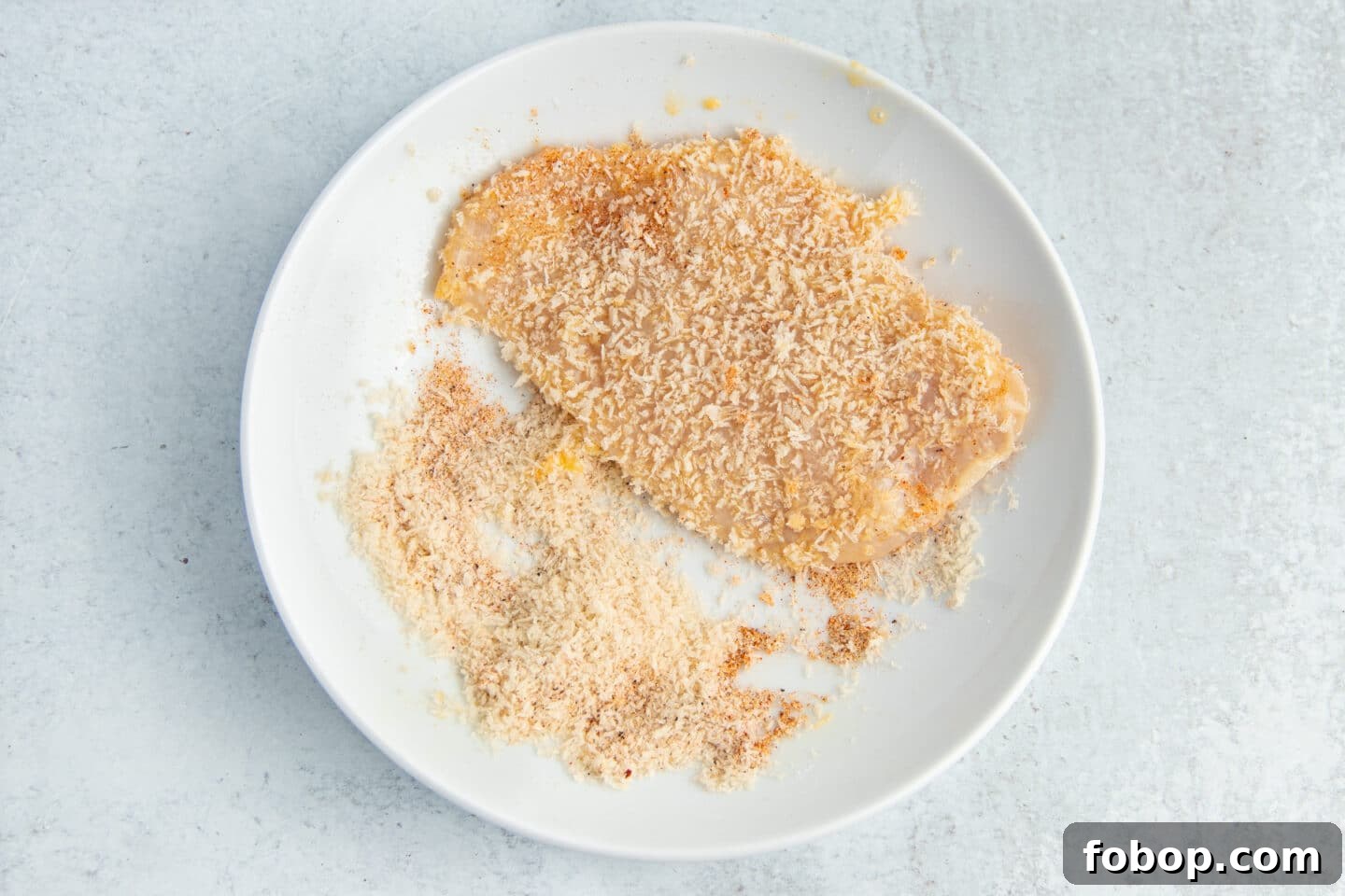This is a picture of a chicken cutlet being dipped in panko.