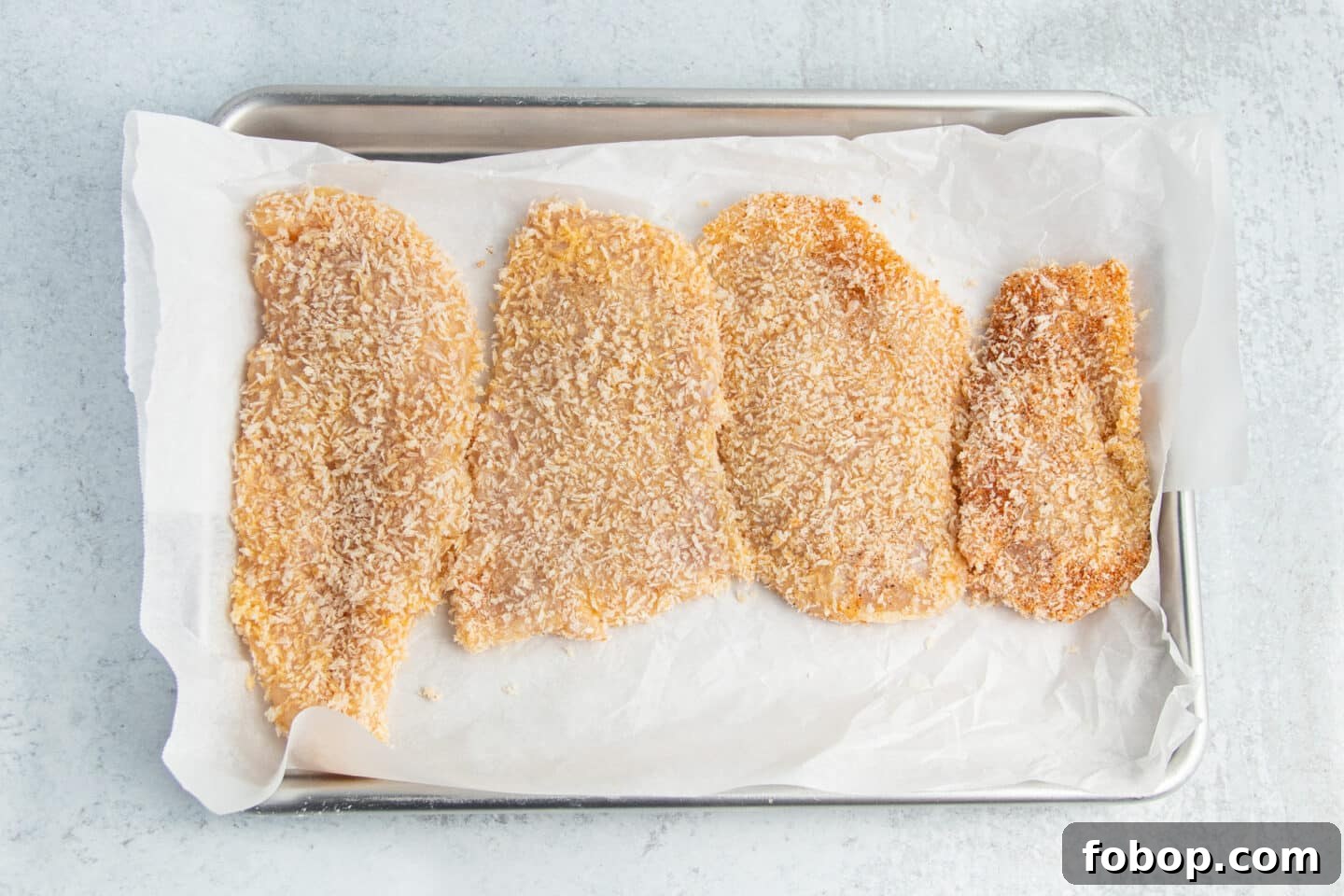 This is a picture of a chicken cutlets on a baking sheet ready to be air fried.