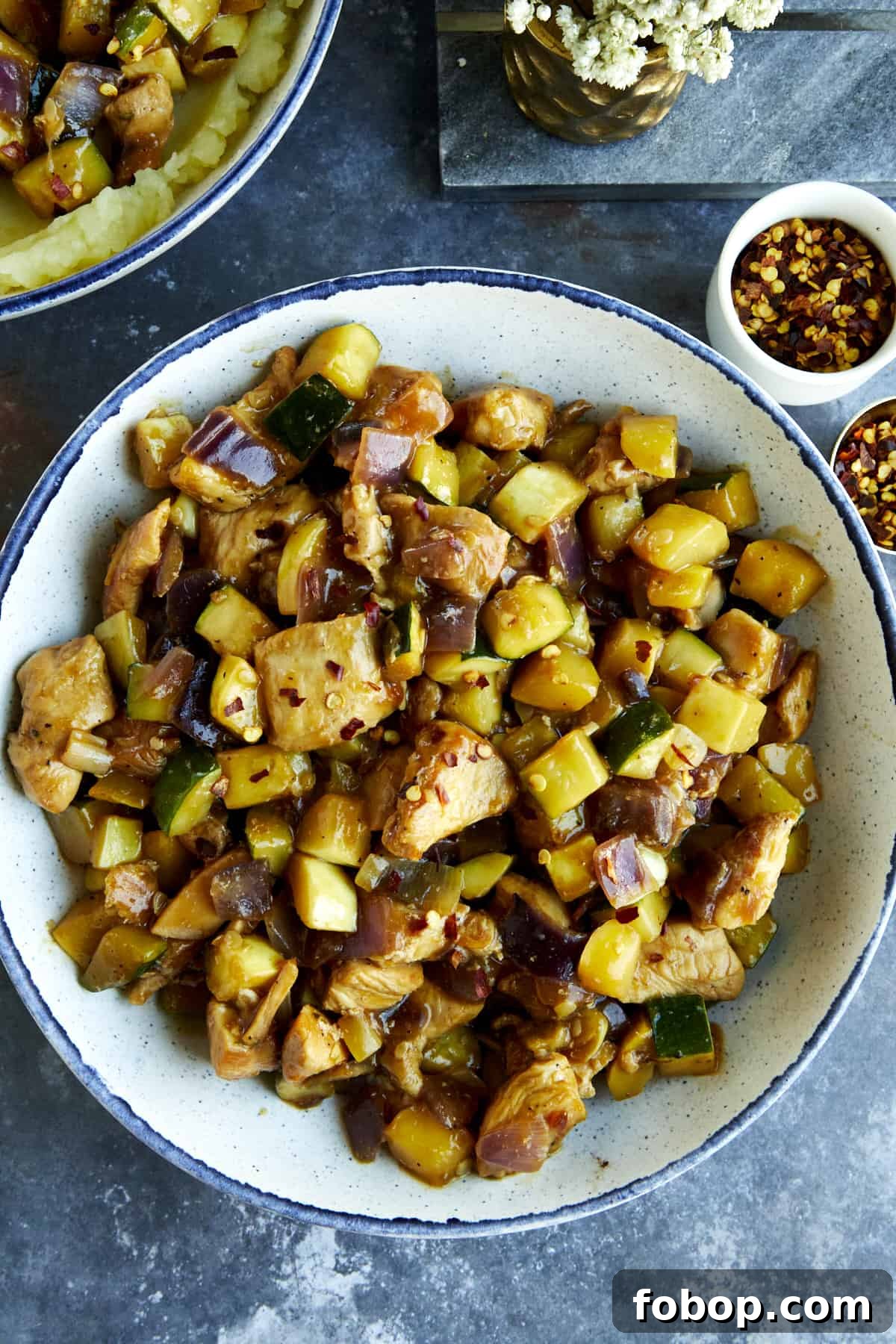 A bowl of chicken and zucchini stir fry.