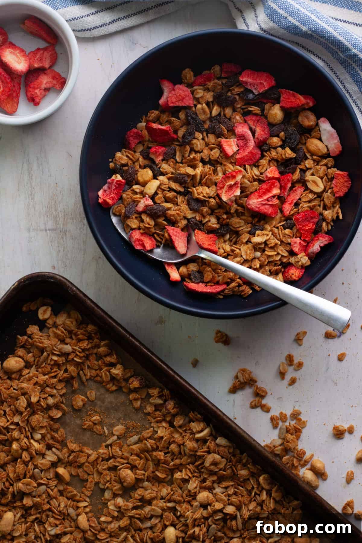 Crunchy Peanut Butter Granola Recipe for Homemade Snacks 2 Peanut butter granola on a baking sheet and a bowl topped with dried strawberries.