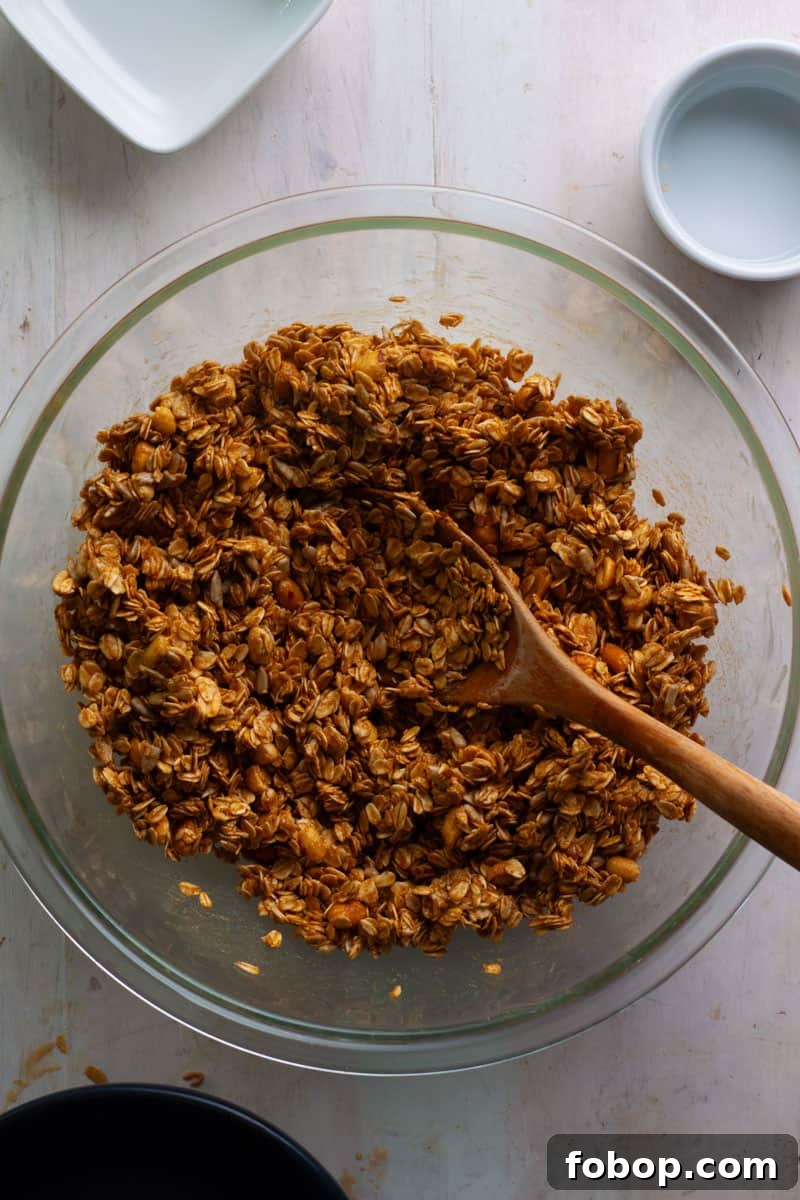 Crunchy Peanut Butter Granola Recipe for Homemade Snacks 5 Homemade peanut butter granola in a large bowl getting mixed together before baking.