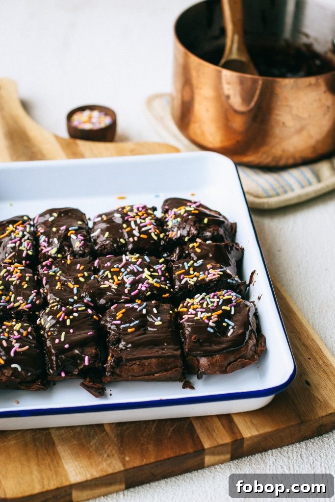 Gluten-Free Cosmic Brownies Recipe — Chewy Chocolate Treats 5 chocolate brownies with sprinkles on a white tray and wood cutting board with a pot of melted chocolate