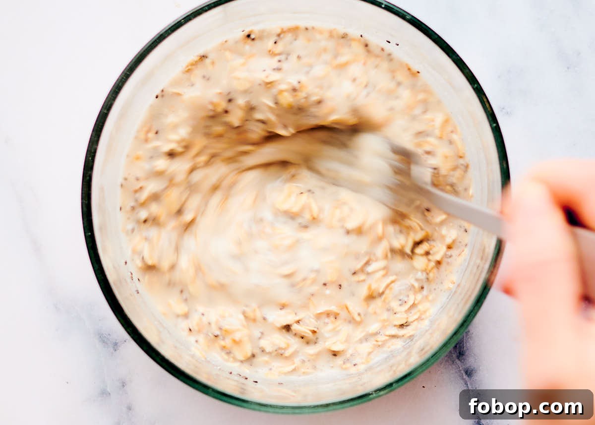Mixing ingredients together for overnight oats in a glass bowl.