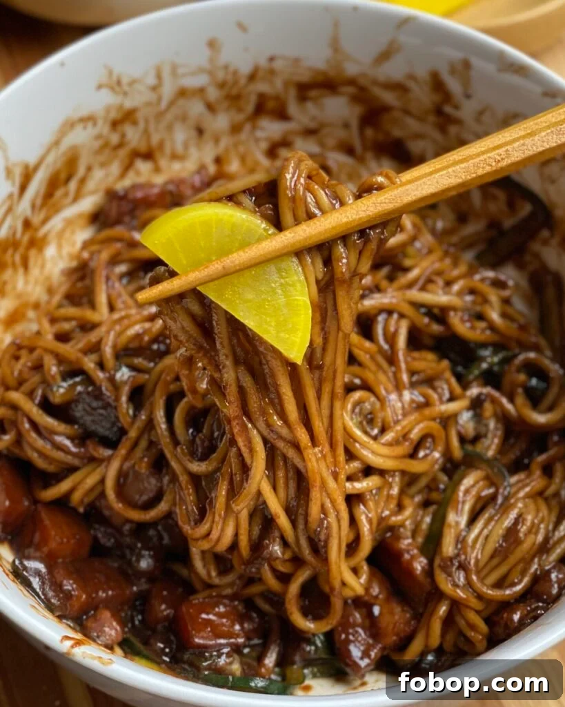 Jajangmyeon: Authentic Korean Black Bean Noodle Recipe 4 Jajangmyeon noodle pull with a piece of yellow pickled radish.