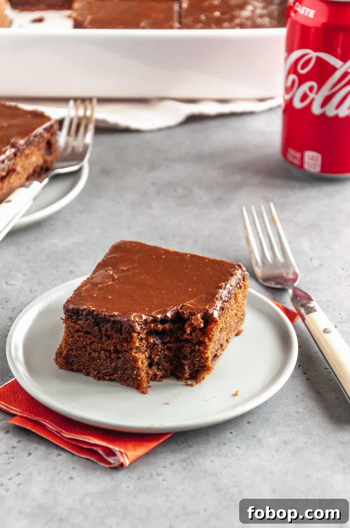 Moist Chocolate Coca-Cola Cake Recipe for Every Occasion 8 slice of coca cola cake with a bite taken out of it served on a round plate with a fork