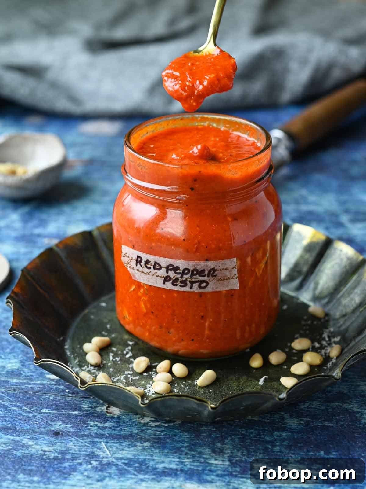 Smoky Roasted Red Pepper Pesto Recipe for Pasta & Sandwiches 2 Red pepper pesto sauce in a jar with a spoon in it dripping into the jar.