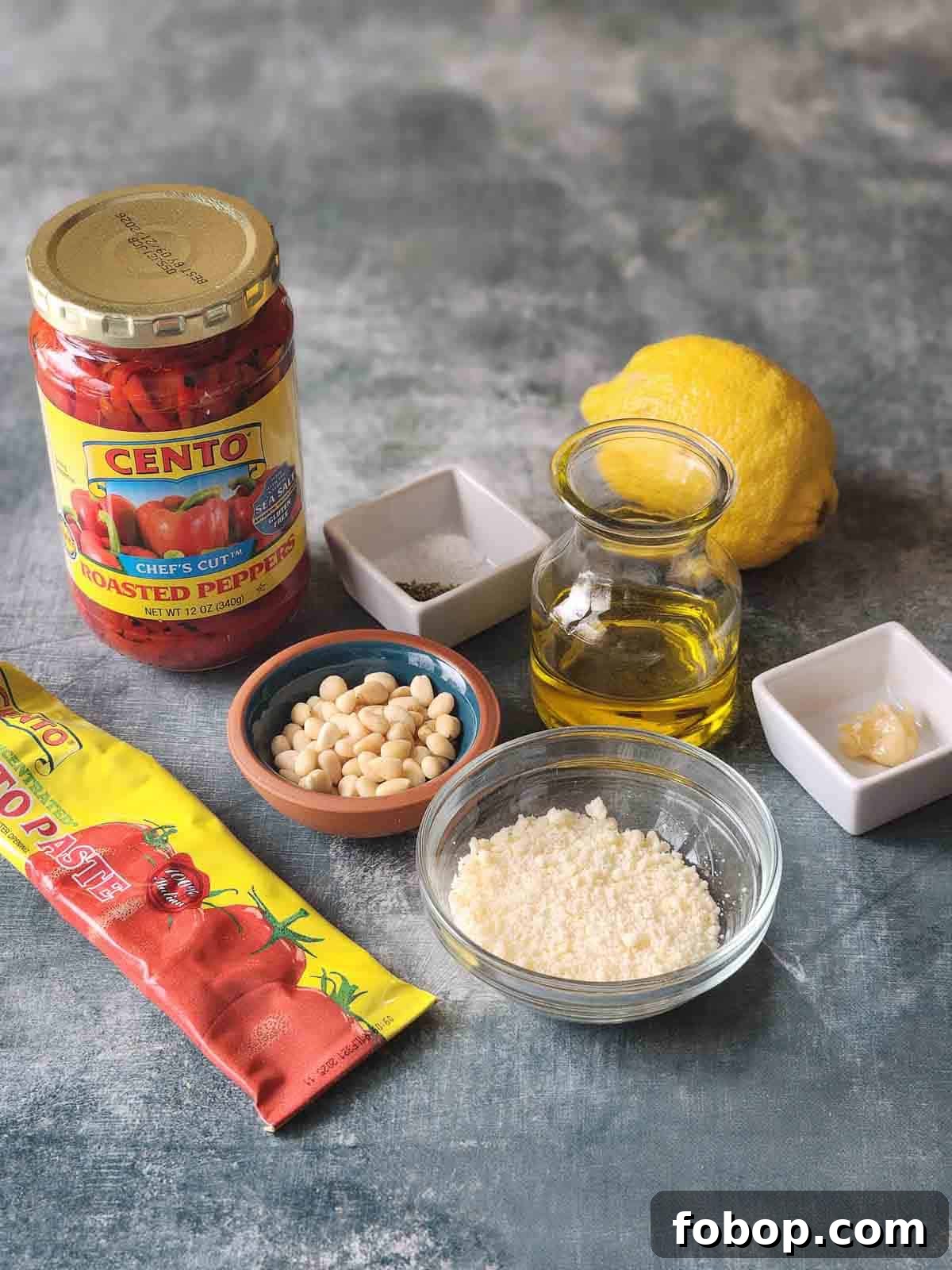 Smoky Roasted Red Pepper Pesto Recipe for Pasta & Sandwiches 3 Ingredients for roasted red pepper pesto on a grey surface.