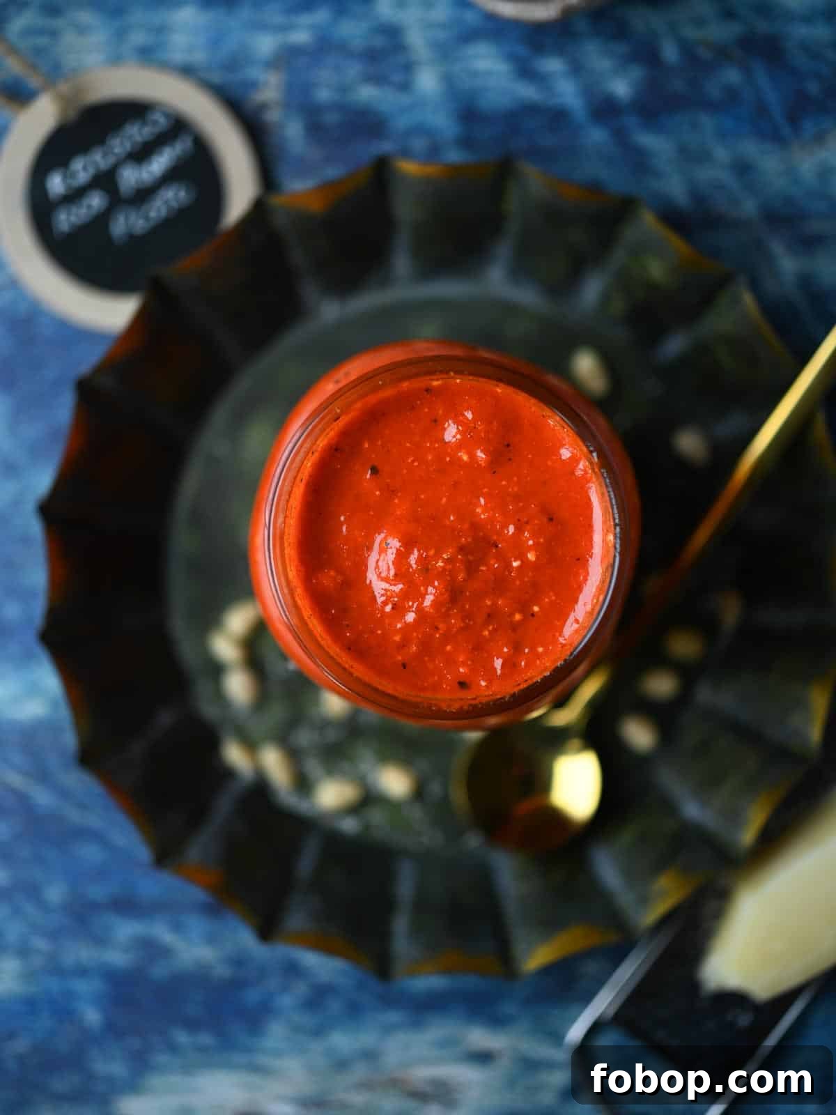 Smoky Roasted Red Pepper Pesto Recipe for Pasta & Sandwiches 7 Overhead of red pepper pesto in a clear jar on top on a round grey plate.