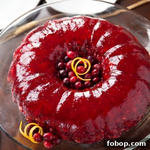red cranberry jello salad in a ring on a glass cake stand