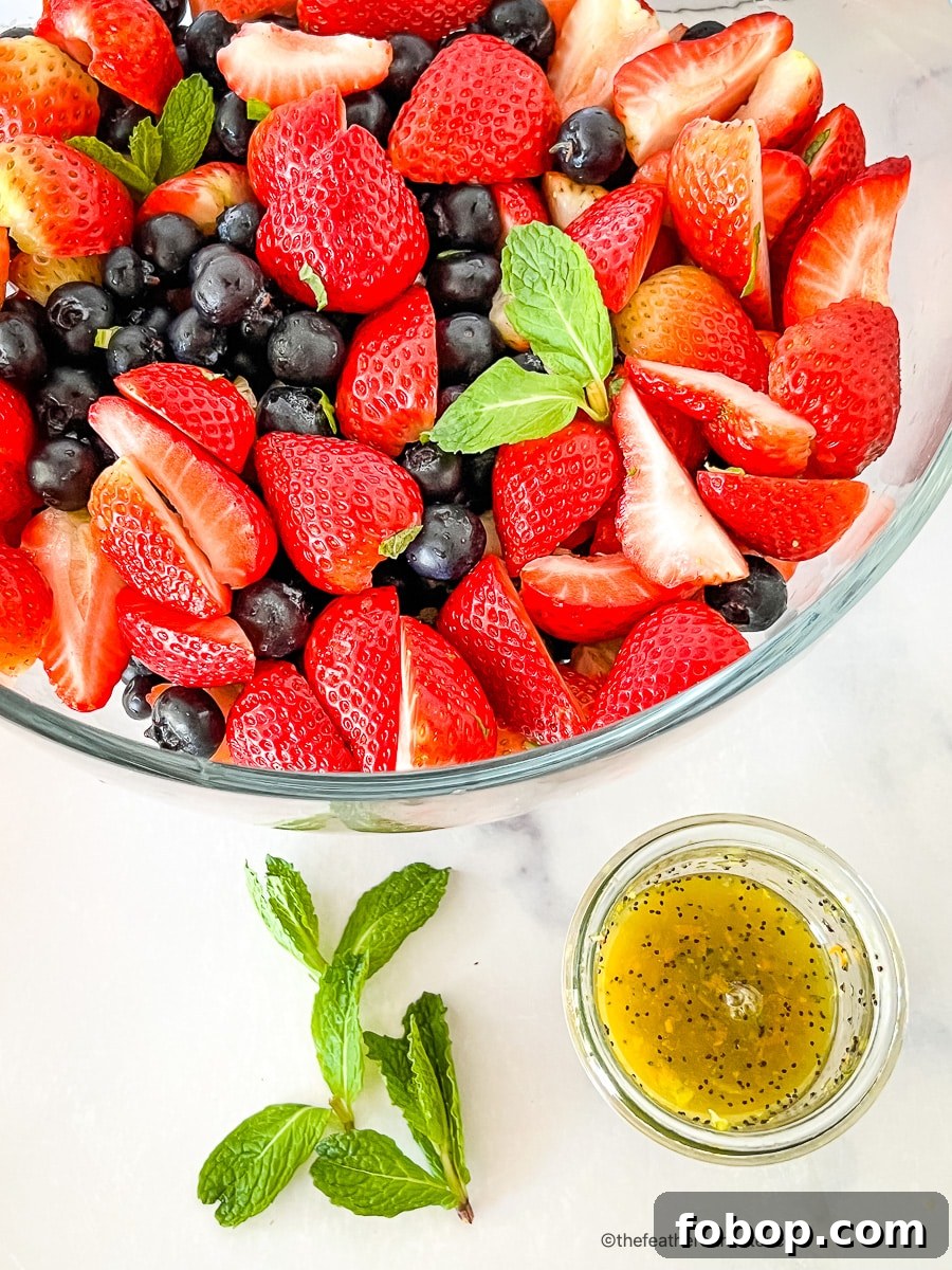 Fresh Blueberry and Strawberry Summer Salad Recipe 6 Bowl of mixed berry salad next to a small bowl of citrus poppy seed dressing.