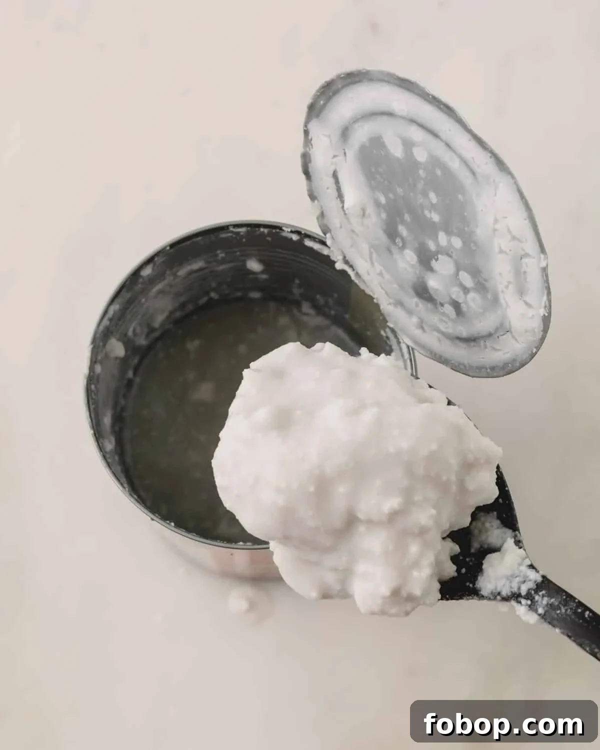 A spoon lifting coconut cream from a can.