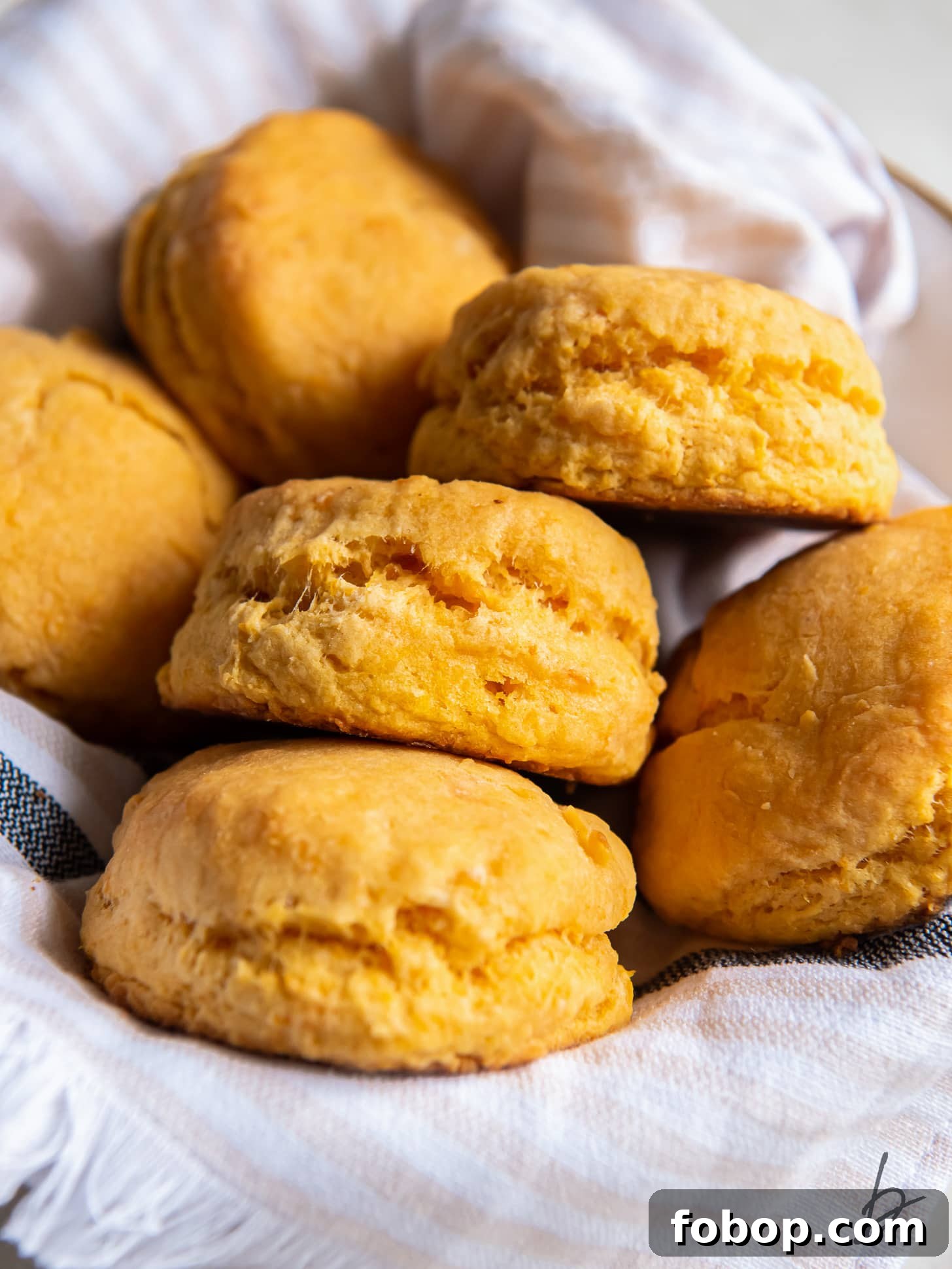 several sweet potato biscuits on a striped kitchen cloth in a bowl.