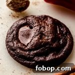 A chocolate cayenne cookie with a cinnamon stick, chili pepper, and nutmeg around it.