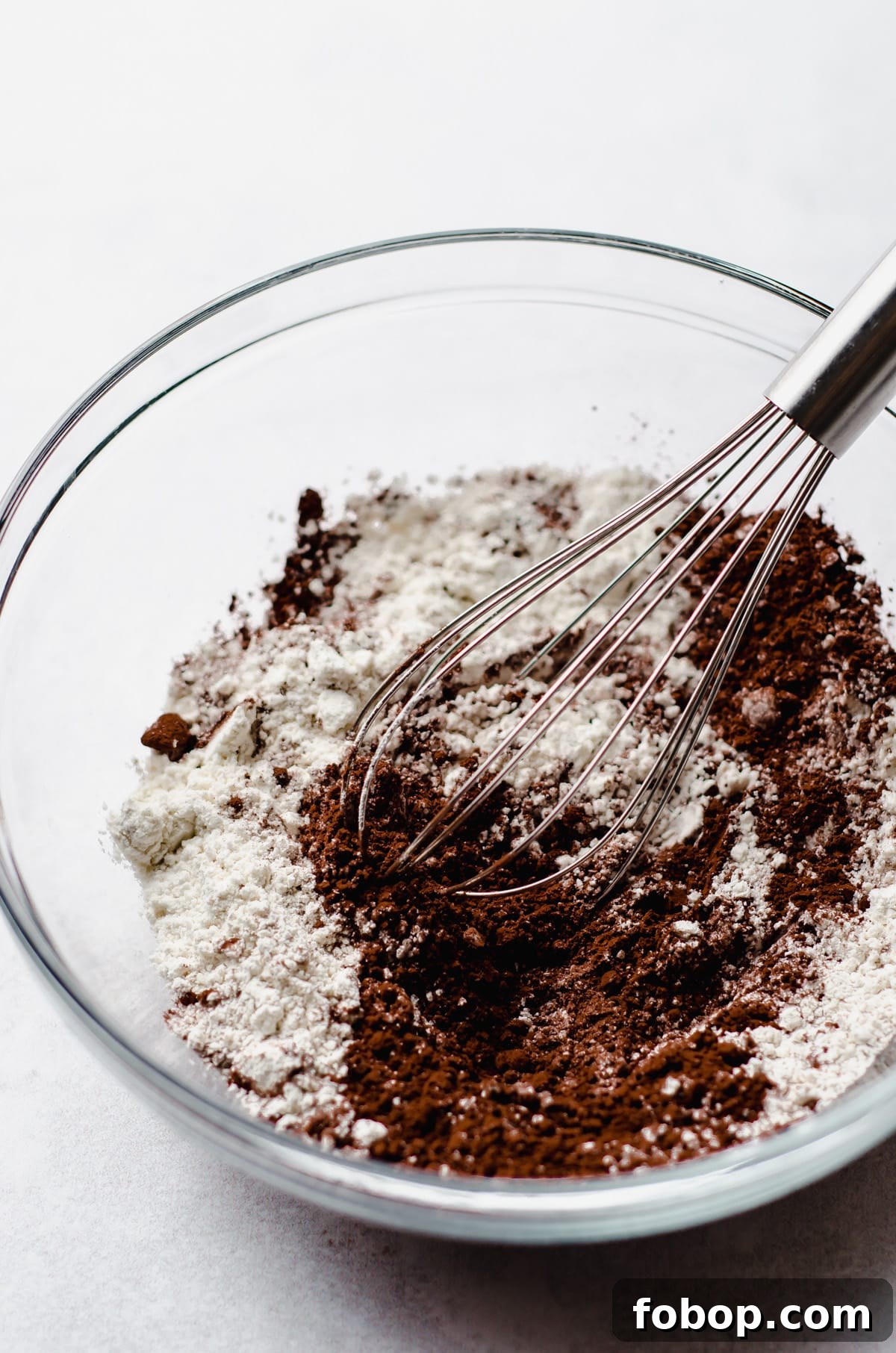 flour and cocoa powder in a glass bowl with a whisk