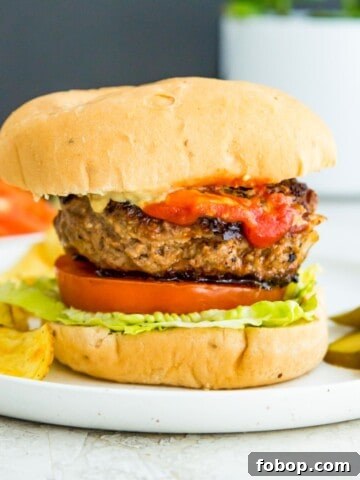 A gluten free burger in a bun with lettuce, tomato and ketchup.