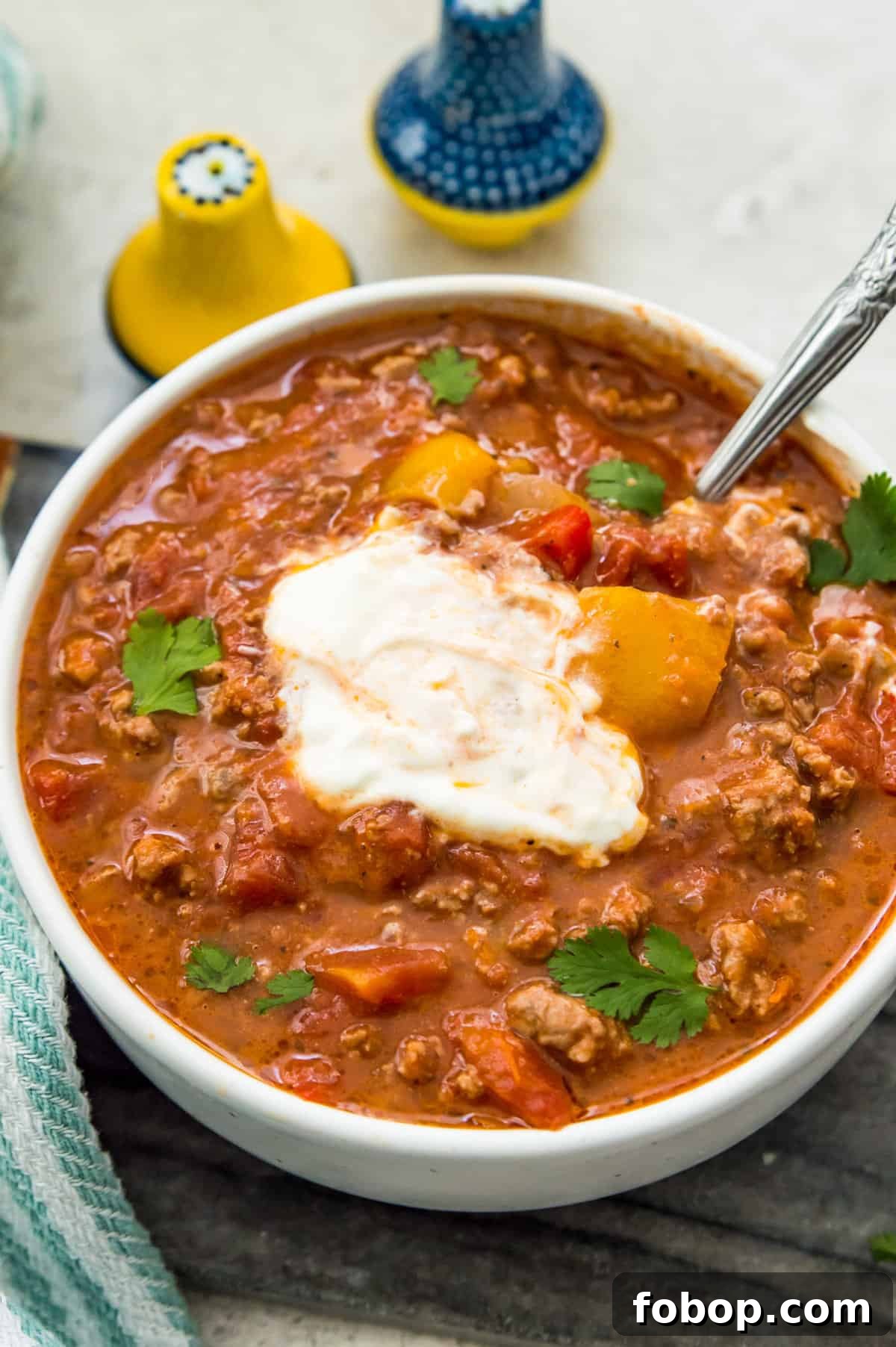 Ground Pork Chili Recipe Without Beans — Hearty Skillet Chili 9 A bowl of chili topped with sour cream and garnished with fresh cilantro.