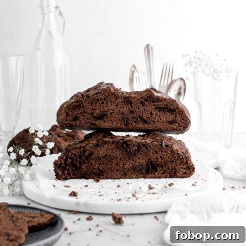 Double Chocolate Irish Stout Soda Bread Recipe for Rich Treat 12 two halves of chocolate soda bread stacked on top of each other on marble surface with white flowers and crumbs around and another loaf of chocolate soda bread behind.